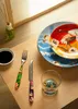 A table setting with Japanese-inspired tableware, including plates, a fork, a knife, a glass, and a soy sauce dish. Voir les images du produit