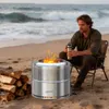A man sits by a bonfire on a beach, holding a mug. Produktbild-Vorschau