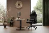 A gaming chair and desk setup in a room with wood-paneled walls and a large window overlooking greenery. Produktbild-Vorschau
