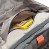 A close-up view inside a backpack, showing a zippered pocket with a pack of Ricola candies inside. Produktbild-Vorschau