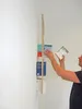 A person is placing books on a wall-mounted shelf. Produktbild-Vorschau