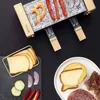 A raclette grill with food items arranged around it. Produktbild-Vorschau