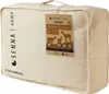 A beige fabric bag containing a blanket, with a product tag attached. Produktbild-Vorschau