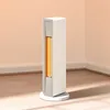A white tower heater with an orange heating element is shown standing on a wooden floor against a light peach wall. Voir les images du produit