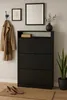 A hallway vignette featuring a black shoe cabinet, a coat and scarf hanging on a hook, a framed picture, a mirror, and a potted snake plant. Produktbild-Vorschau