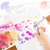 A child's hand is using a battery-operated airbrush marker set to decorate a white t-shirt with an underwater theme. Voir les images du produit