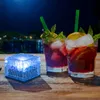 Two cocktails and a glowing blue ice cube light sit on a wooden table at night, with a blurred background of water and lights. Produktbild-Vorschau