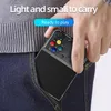 A hand is holding a black handheld gaming console, placing it into a pair of blue jeans. Produktbild-Vorschau