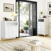 A bright, modern living room scene with two white storage cabinets, one on the left and one on the right, positioned near a large open doorway leading to an outdoor patio with plants. A rug and a coffee table are in the foreground. Podgląd zdjęcia produktu
