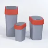 Three different sized trash cans with red lids and gray bodies are arranged on a white background. Podgląd zdjęcia produktu