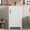 A white freestanding bathroom cabinet with a black faucet and a round mirror in the background. Produktbild-Vorschau