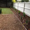 A backyard scene with a gravel path, a lawn, and a garden bed along a white fence. Voir les images du produit