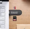A USB-C card reader/writer is connected to a laptop, with a micro SD card and an SD card placed nearby on a wooden surface. Produktbild-Vorschau