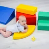 A baby is playing with colorful foam blocks on a light-colored floor. Produktbild-Vorschau