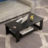 A black coffee table with a shelf is placed on a gray patterned rug in front of a light gray sofa. A laptop, a cup of coffee, and a small vase of yellow flowers are on the table. Produktbild-Vorschau