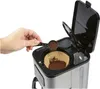 A hand is adding coffee grounds to a coffee filter in a coffee maker. Anteprima dell’immagine prodotto