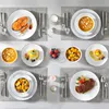 A table setting with multiple place settings, each featuring a plate with food, cutlery, and a placemat. Produktbild-Vorschau