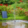 A solar-powered fountain in a garden pond, with a solar panel nearby. Produktbild-Vorschau