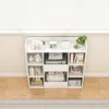 A white shelving unit filled with books and decorative items, placed against a wall with a window blind above. Náhľad obrázku produktu