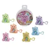 A collection of small, fuzzy teddy bear toys, each with a baby bottle and a keychain, displayed around their packaging. Anteprima dell’immagine prodotto