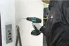 A person is drilling a hole in a wall next to an elevator call button. Produktbild-Vorschau