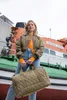 A woman stands in front of a boat, holding a duffel bag. Voir les images du produit