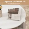 A white round coffee table with magazines on top, next to a vase with flowers. Produktbild-Vorschau