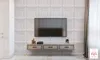 A modern living room with a wall-mounted TV and a floating media console against a textured wall. Produktbild-Vorschau