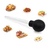 A turkey baster is shown in the center, surrounded by various cooked food items like roasted chicken, ham, stew, fried chicken, and fried eggs. Produktbild-Vorschau