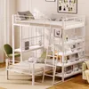 A white metal bunk bed with shelves and a ladder, set up in a room with a green chair and some wall art. Produktbild-Vorschau