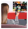 A woman is sitting on a couch, holding a remote control and watching TV. The TV screen displays a grid of movie or show thumbnails. Produktbild-Vorschau