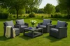 An outdoor furniture set with cushions and a coffee table is arranged on a green lawn in a garden setting. Anteprima dell’immagine prodotto