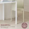 A close-up view of the leg and underside of a white table, with a beige chair partially visible behind it, set against a light-colored wall and floor. Anteprima dell’immagine prodotto