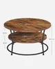 A two-tiered round coffee table with a wood-grain finish and black metal legs, shown against a white background with dimensions indicated. Produktbild-Vorschau