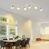 A dining room with a track light fixture, a wooden dining table with chairs, and large windows. Produktbild-Vorschau