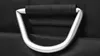 A close-up of a silver handle with a black fabric grip, attached to a black textured surface. Náhled obrázku produktu