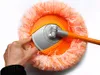 A hand is shown adjusting the head of a fluffy orange mop on a white background. Náhled obrázku produktu