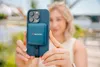A woman is holding a smartphone with a blue Verbatim SnapBack SSD attached to the back. Náhľad obrázku produktu