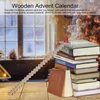 A wooden advent calendar in the shape of stairs with numbers on each step, placed on a wooden table in front of a blurred window with a snowy scene and a Christmas tree. Produktbild-Vorschau