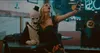 A woman in a costume takes a selfie with a clown character in a dimly lit diner. Produktbild-Vorschau