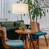A cozy seating area with a green sofa, wooden chairs, a small wooden table with a potted plant, and a large floor lamp. Voir les images du produit