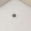 A close-up view of a white shower tray with a square drain cover. Produktbild-Vorschau