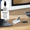A white USB hub with multiple ports is connected to a laptop on a wooden desk. A USB drive is plugged into the hub, and another USB drive is placed next to it. A monitor is visible in the background. Podgląd zdjęcia produktu