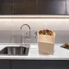 A kitchen sink area with a paper bag filled with compostable materials next to it. Produktbild-Vorschau