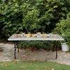 A folding table set up outdoors with food and drinks on it, surrounded by greenery. Produktbild-Vorschau
