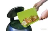 A person is shown discarding onion peels into a trash can using a green cutting board. Produktbild-Vorschau