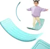 A young child is balancing on a turquoise wobble board. Podgląd zdjęcia produktu