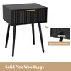 A black nightstand with a drawer and gold handle, shown from a three-quarter angle. An inset image highlights the stability mount plates on the legs. Text at the bottom reads "Solid Pine Wood Legs". Produktbild-Vorschau