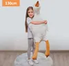 A young girl is hugging a large stuffed goose toy. Podgląd zdjęcia produktu