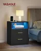 A black nightstand with gold handles and blue LED lighting is placed next to a bed. Náhled obrázku produktu